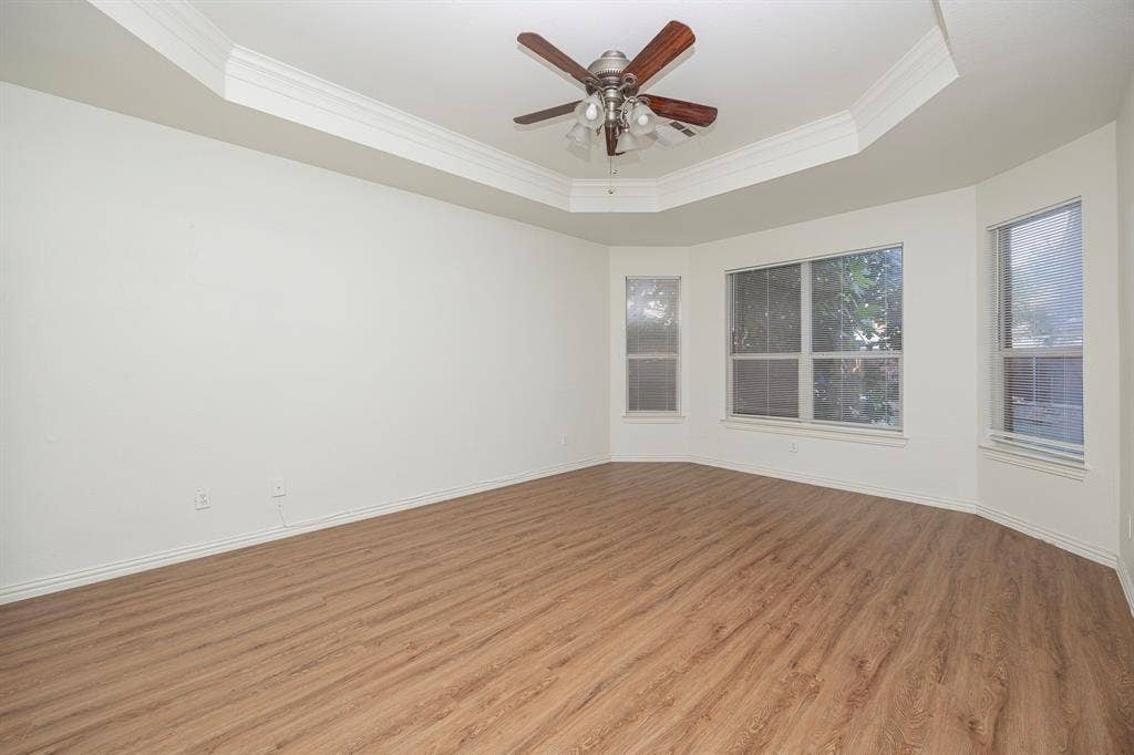 6405 Sapphire Drive, McKinney, TX 75070 Tray ceiling with crown molding, wood-finish flooring, ceiling fan, and bay window