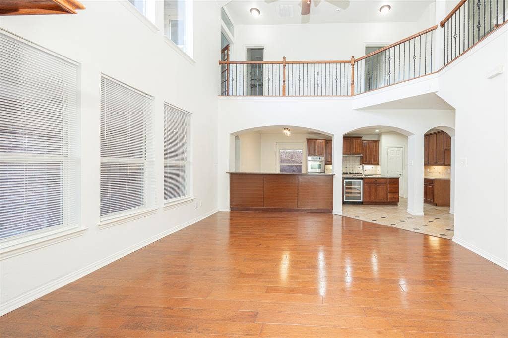 6405 Sapphire Drive, McKinney, TX 75070 Expansive living area with high ceilings, wood-finish flooring, and multiple windows