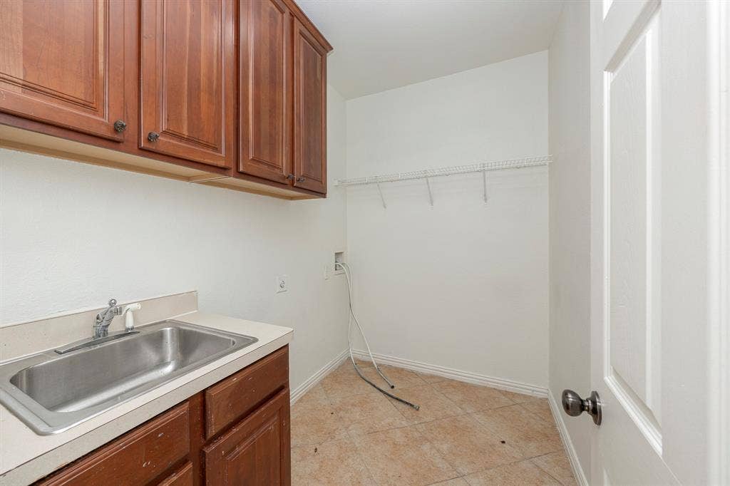 6405 Sapphire Drive, McKinney, TX 75070 White walls, wood cabinetry, stainless steel sink, tiled flooring, and a white paneled door
