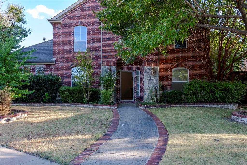 6405 Sapphire Drive, McKinney, TX 75070 Brick exterior with stone accents, arched windows, and a curved paved walkway with brick edging