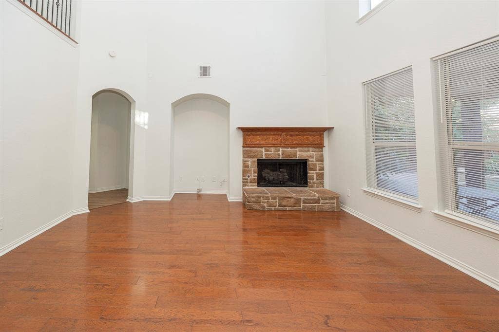 6405 Sapphire Drive, McKinney, TX 75070 High ceilings, wood-finish flooring, stone-clad fireplace with wood mantel, arched doorways, and multiple windows