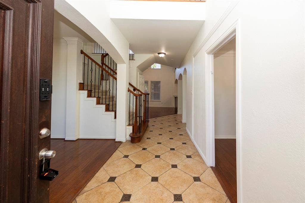 6405 Sapphire Drive, McKinney, TX 75070 Entryway featuring patterned tile flooring, wood-finish flooring, a grand staircase with wrought iron balusters, and arched doorways