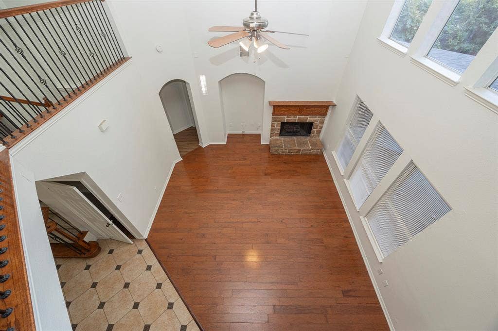 6405 Sapphire Drive, McKinney, TX 75070 Two-story great room with hardwood-finish flooring, stone-surround fireplace with wood mantle, and multiple large windows