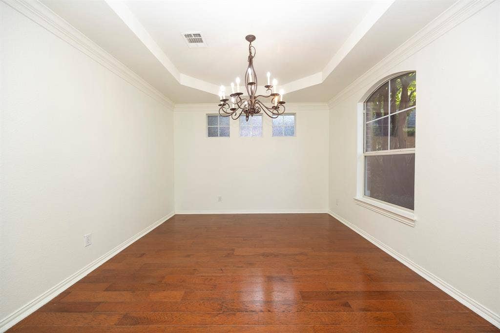 6405 Sapphire Drive, McKinney, TX 75070 Wood-finish flooring with a tray ceiling and chandelier