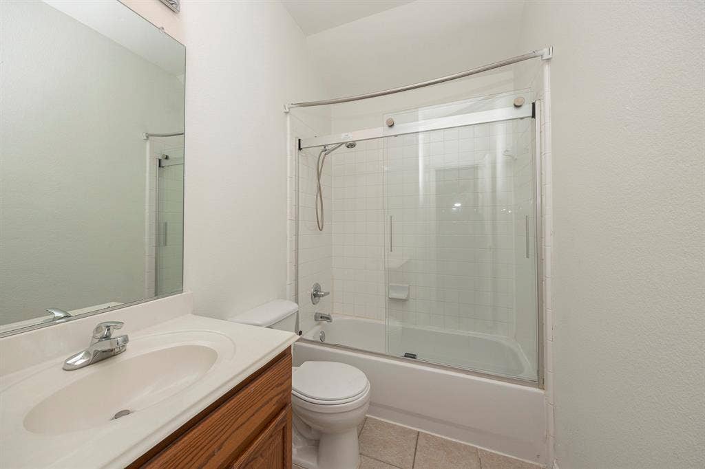 6405 Sapphire Drive, McKinney, TX 75070 Bathroom featuring a wood-finish vanity with an integrated sink, polished chrome faucet, and a large wall-mounted mirror