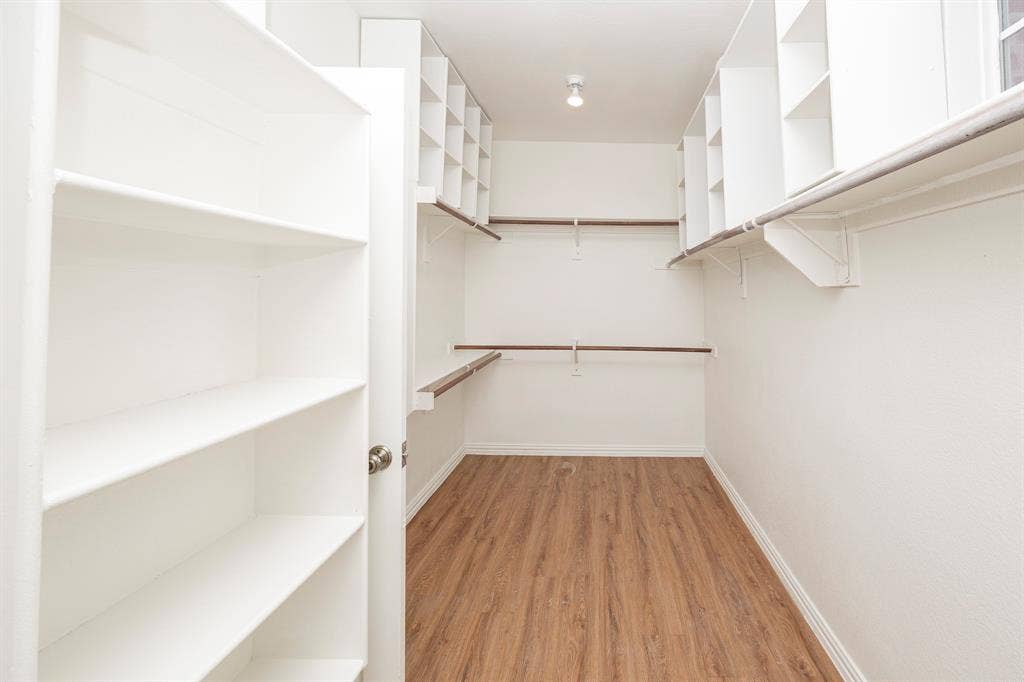 6405 Sapphire Drive, McKinney, TX 75070 Walk-in closet featuring wood-finish flooring, built-in shelving, integrated storage cubbies, and multiple clothing rods