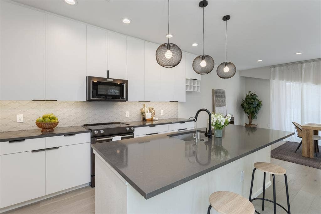 Kitchen with light wood finished floors, a kitchen bar, white cabinets, and stainless steel appliances