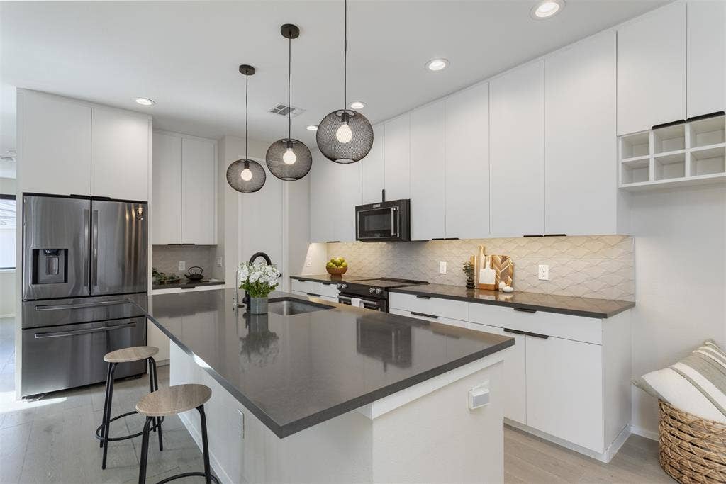 Kitchen with stainless steel fridge, a kitchen bar, white cabinets, modern cabinets, and electric range