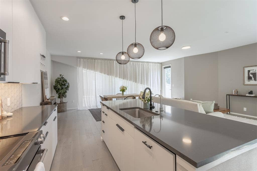 Kitchen with white cabinets, an island with sink, modern cabinets, electric stove, and light wood finished floors
