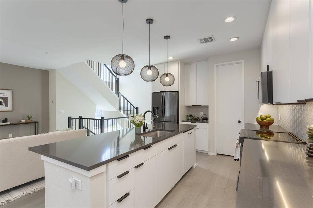 Kitchen with white cabinets, a center island with sink, modern cabinets, and stainless steel refrigerator with ice dispenser
