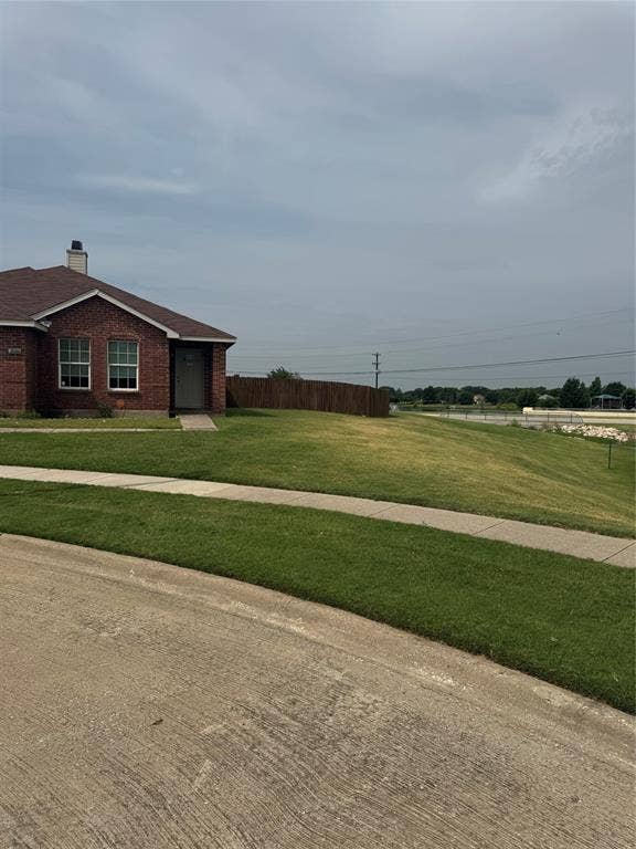 Red brick exterior, shingled roof, front entry, front yard, concrete sidewalk