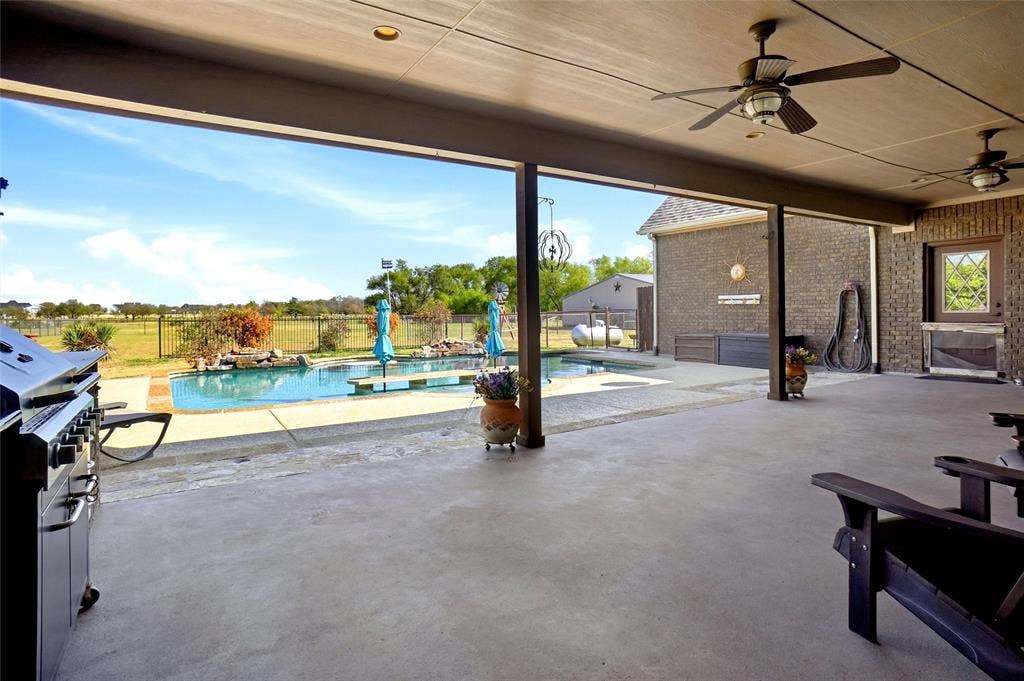 Covered patio with ceiling fans, grill, mini refrigerator and sink.