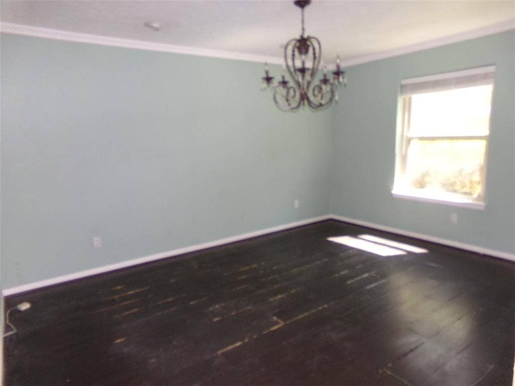211 S Alexander Avenue, Duncanville, TX 75116 Crown molding accents a room with a single window and dark wood-finish flooring, complemented by a decorative chandelier