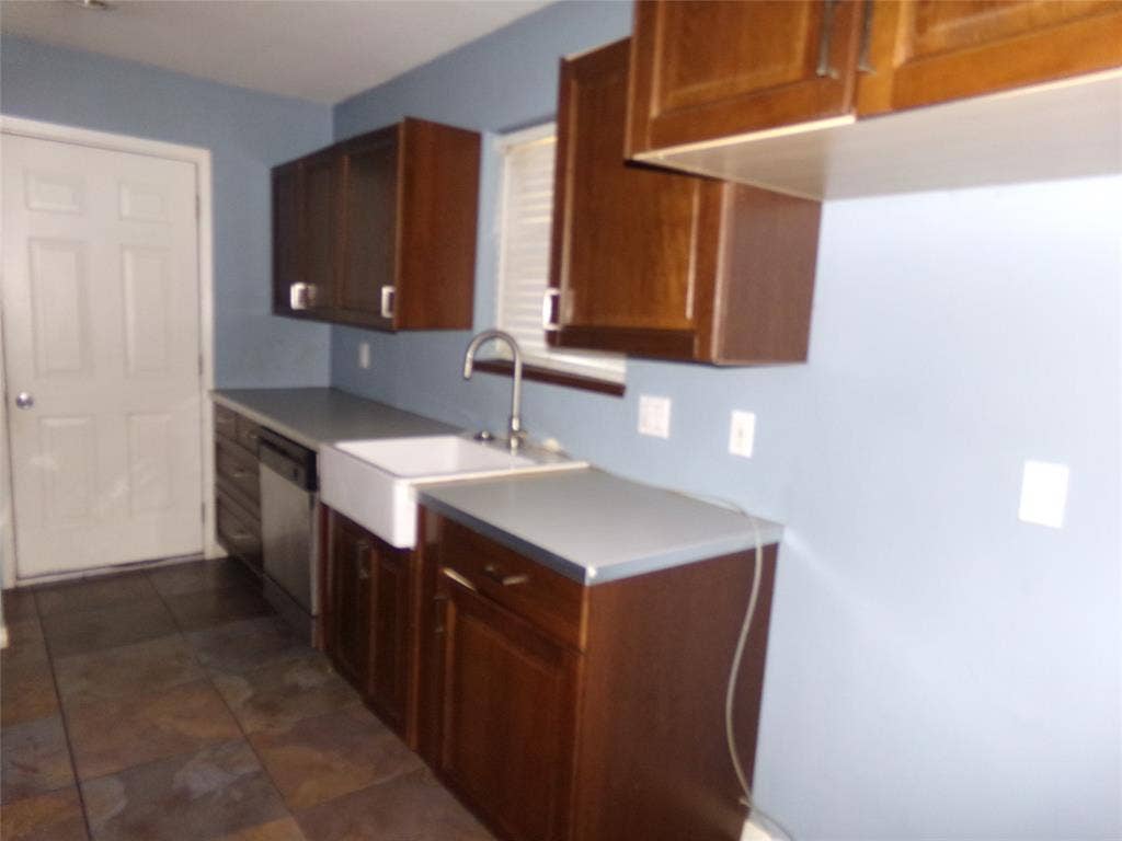211 S Alexander Avenue, Duncanville, TX 75116 Rich wood cabinetry, an apron-front sink, stainless steel dishwasher, and tiled flooring