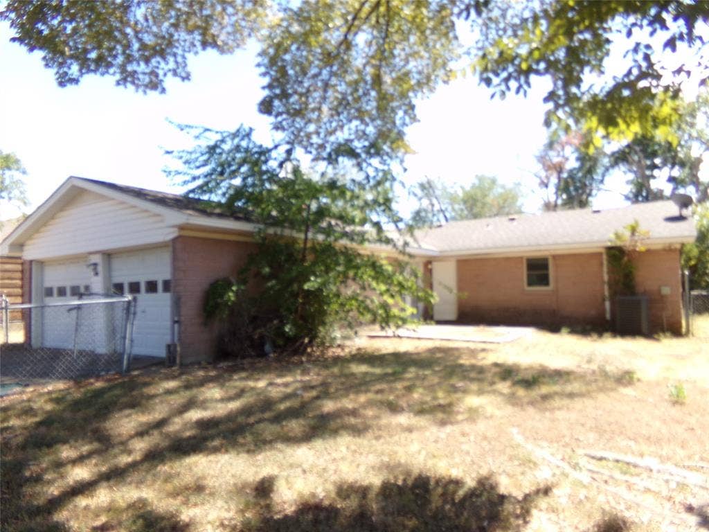 211 S Alexander Avenue, Duncanville, TX 75116 Brick exterior with an attached two-car garage, white garage doors, and a patio area