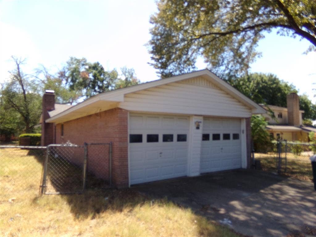 211 S Alexander Avenue, Duncanville, TX 75116 Two-car garage with white paneled doors, brick exterior, and a side chimney
