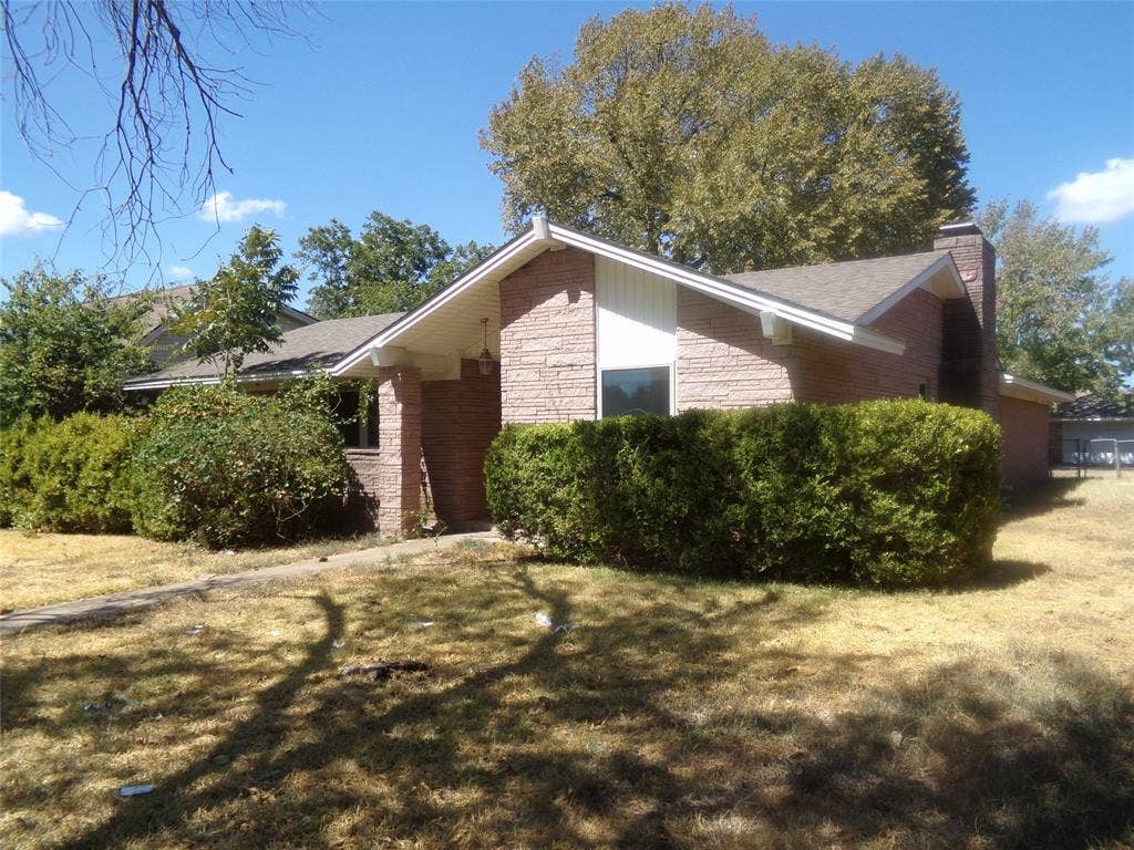 211 S Alexander Avenue, Duncanville, TX 75116 Brick exterior with a gabled roofline, front entryway, prominent chimney, and established shrubbery