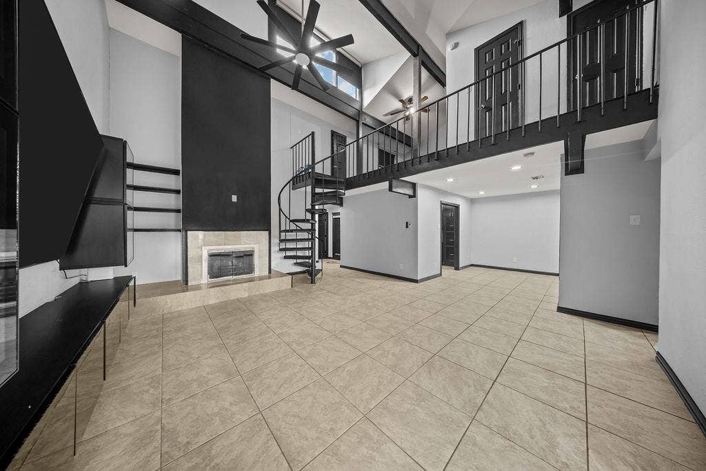 9302 Chimney Sweep Lane, Dallas, TX 75243 Vaulted ceiling with exposed beams, spiral staircase, fireplace with stone surround, loft with metal railing, and tile flooring
