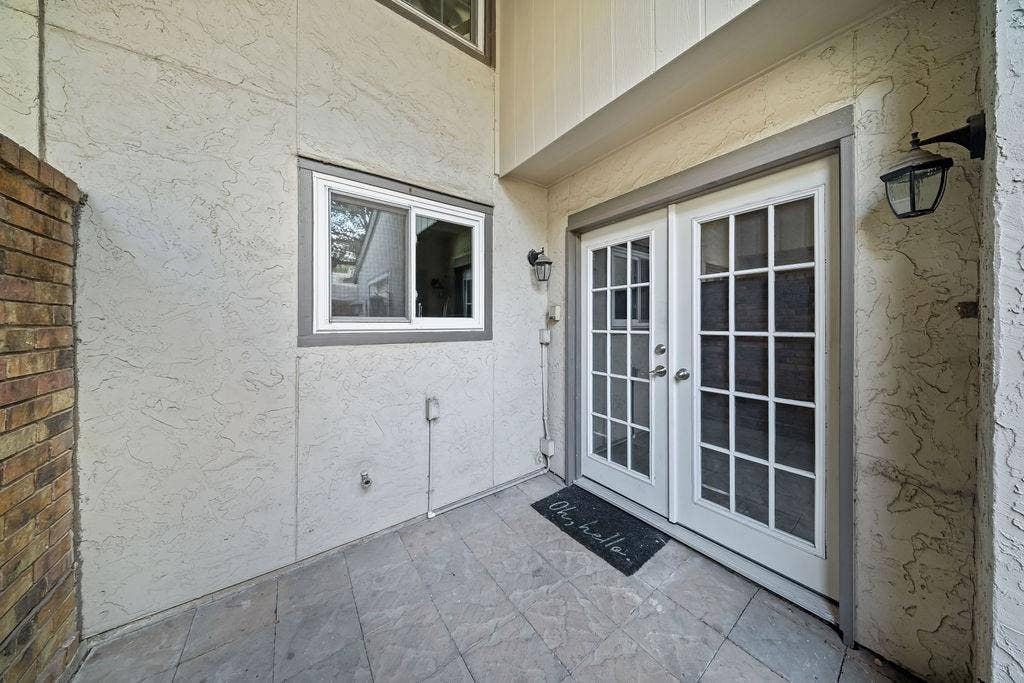 9302 Chimney Sweep Lane, Dallas, TX 75243 Double French doors with divided lites, stucco exterior, brick accent wall, and a sliding window