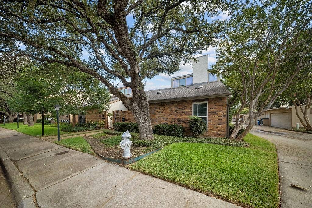 9302 Chimney Sweep Lane, Dallas, TX 75243 Brick exterior with white trim, a gabled roof, and multiple windows