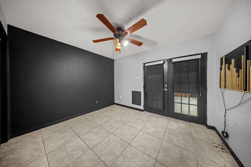 9302 Chimney Sweep Lane, Dallas, TX 75243 Ceramic tile flooring, black accent wall, ceiling fan with light fixture, and French doors with privacy screens