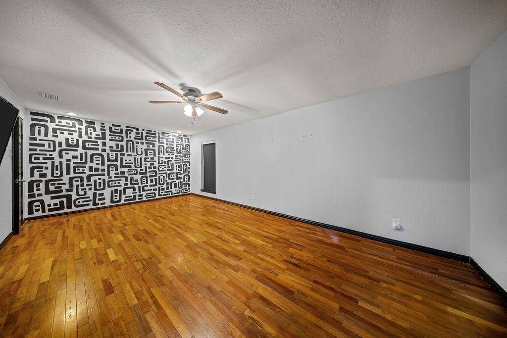 9302 Chimney Sweep Lane, Dallas, TX 75243 Wood-finish flooring, ceiling fan with light fixture, and a decorative accent wall