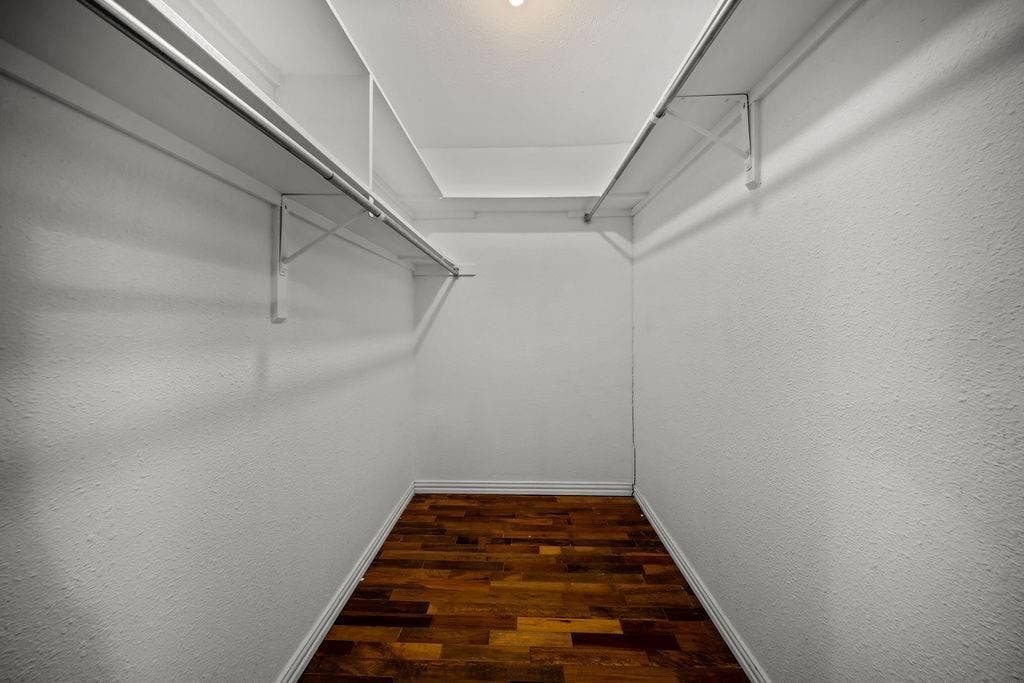 9302 Chimney Sweep Lane, Dallas, TX 75243 Walk-in closet with wood-finish flooring and integrated shelving