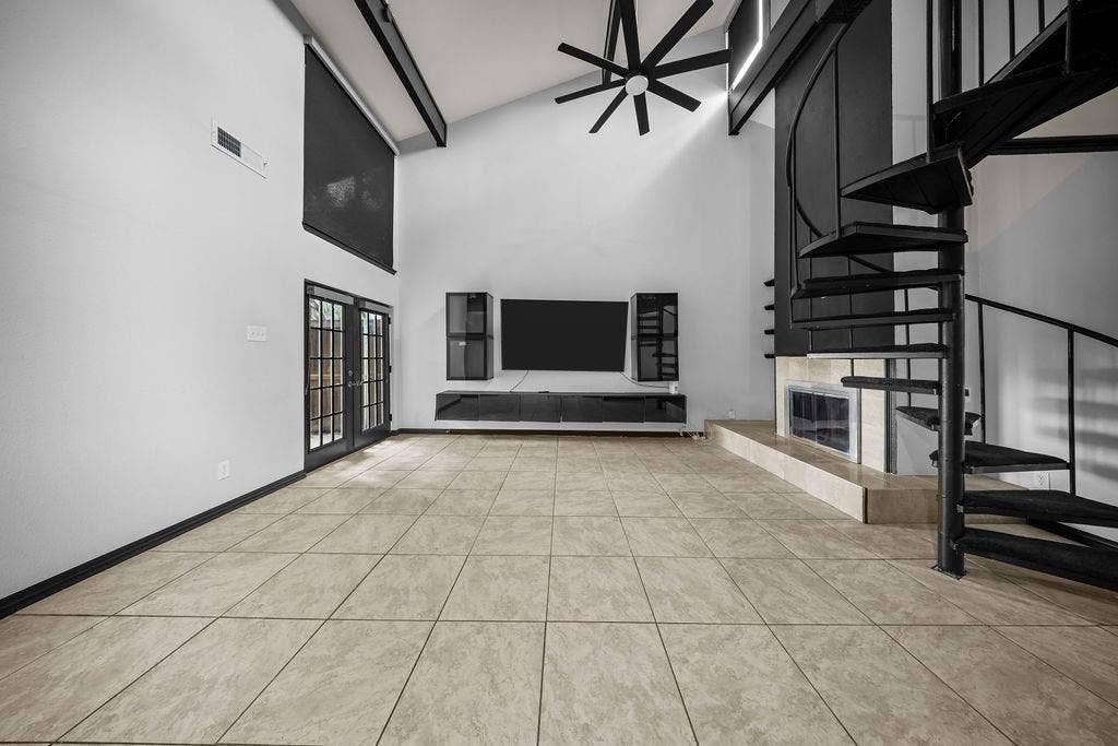 9302 Chimney Sweep Lane, Dallas, TX 75243 Vaulted ceiling with exposed beams, spiral staircase, floor-to-ceiling fireplace, tile flooring, and glass-paneled double doors