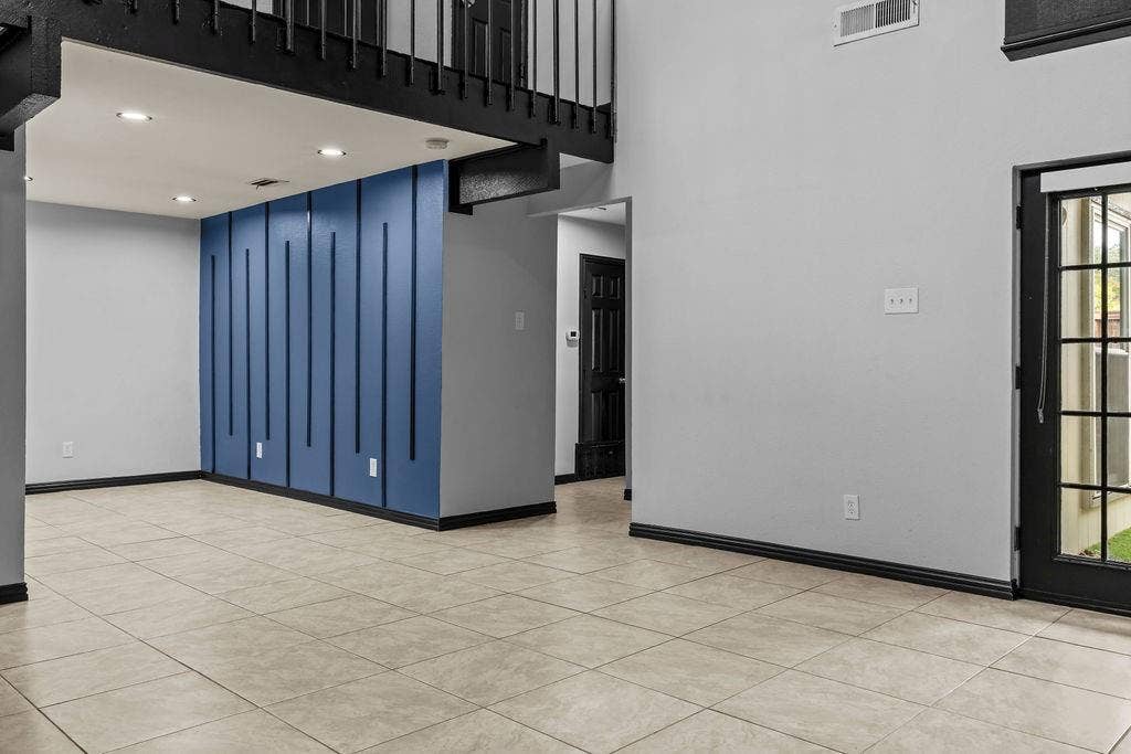 9302 Chimney Sweep Lane, Dallas, TX 75243 Two-story ceiling, tile flooring, accent wall with vertical paneling, recessed lighting, and a glass-paneled exterior door