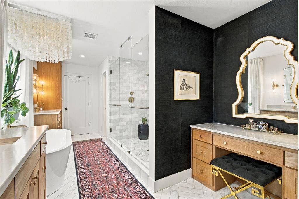 46 Crown Place, Richardson, TX 75080 Glass-enclosed shower with subway tile surround, standalone soaking tub, dual vanities with integrated sinks, wood-finish cabinetry, and a dedicated vanity desk with a stone countertop