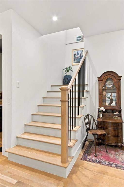 46 Crown Place, Richardson, TX 75080 Hardwood flooring and staircase with natural wood treads, white risers, and a black metal spindle railing