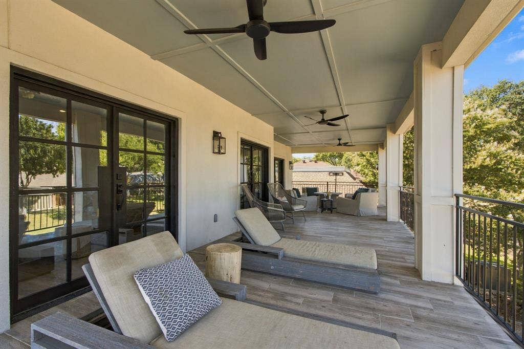 46 Crown Place, Richardson, TX 75080 Expansive covered patio featuring wood-look tile flooring, a coffered ceiling with integrated fans, and a black wrought iron railing