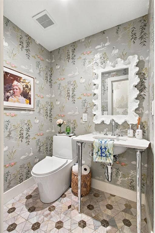 46 Crown Place, Richardson, TX 75080 Patterned wallpaper, geometric tile flooring, white pedestal sink, white toilet, decorative wall mirror