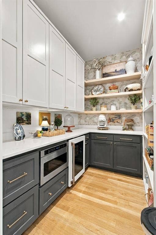 46 Crown Place, Richardson, TX 75080 Built-in microwave, undercounter beverage cooler, wood-finish flooring, white upper cabinetry, and contrasting gray lower cabinetry