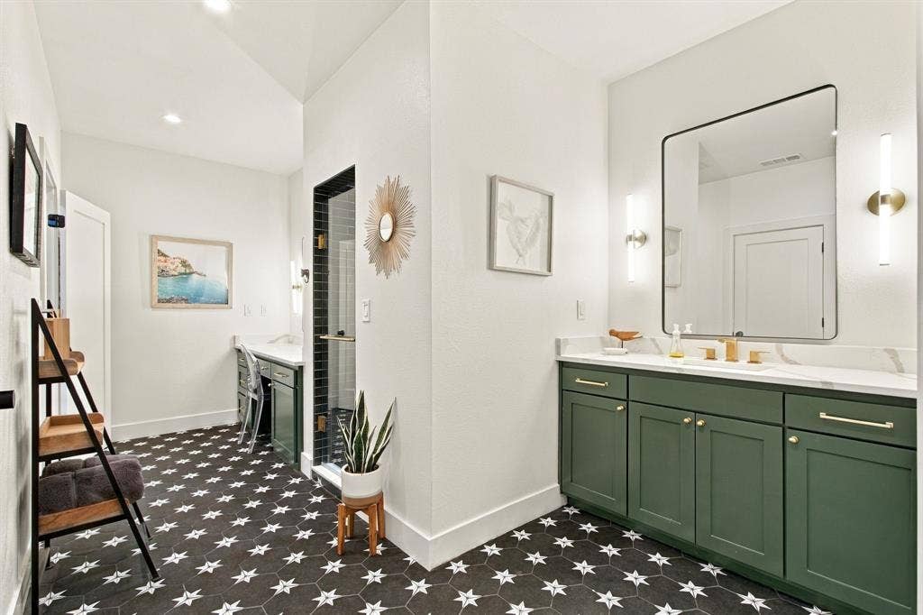 46 Crown Place, Richardson, TX 75080 Hexagonal floor tiles with star accents, vanity with green cabinetry, double sinks, modern wall-mounted light fixtures, and a frameless shower with dark subway tile