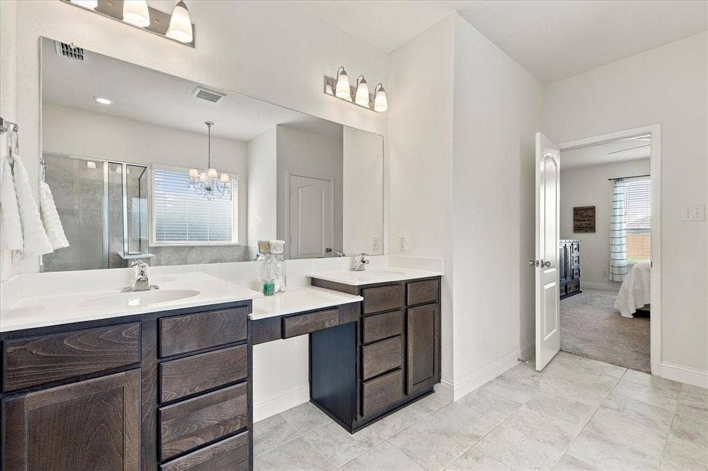 Primary bathroom with shower, dual vanities, and garden tub featuring a chandelier above.