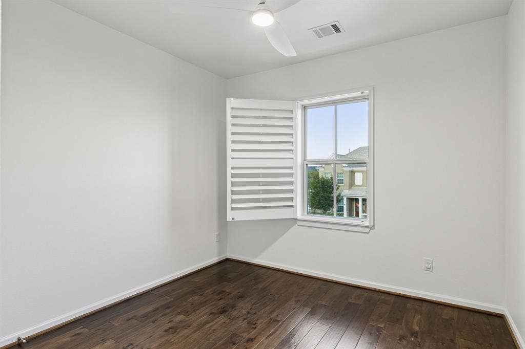 2221 Tremont Boulevard, McKinney, TX 75071 Wood-finish flooring, white walls, and a window with white plantation shutters