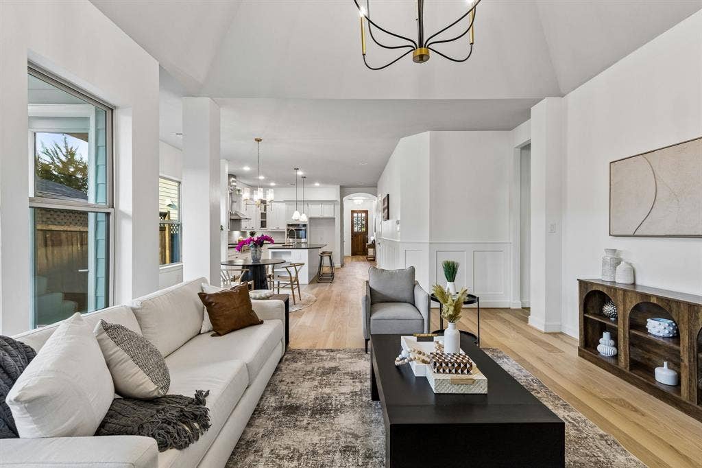2221 Tremont Boulevard, McKinney, TX 75071 Vaulted ceiling with modern chandelier, light wood-finish flooring, white paneled wall accents and recessed lighting