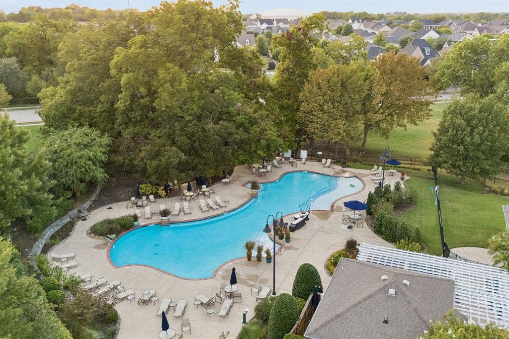 2221 Tremont Boulevard, McKinney, TX 75071 Resort-style pool with integrated steps, surrounding concrete patio, lounge chairs, and umbrella-shaded tables