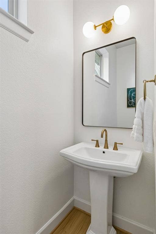 2221 Tremont Boulevard, McKinney, TX 75071 Pedestal sink with champagne bronze-finish faucet, rectangular framed mirror, and two-light vanity fixture