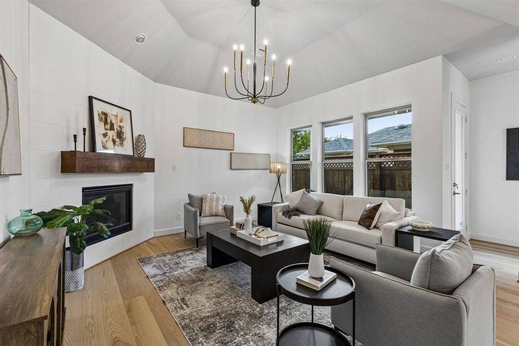 2221 Tremont Boulevard, McKinney, TX 75071 Vaulted ceiling with an elegant chandelier, a corner fireplace featuring a substantial wood mantel, white oak flooring