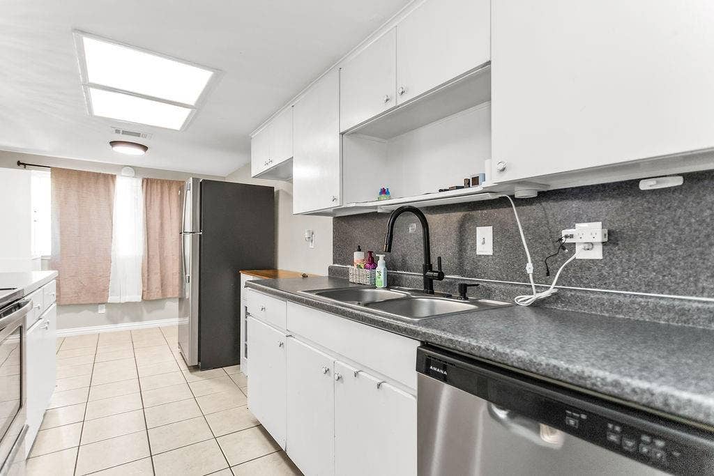 2914 Harvard Street N, Irving, TX 75062 White cabinetry with chrome hardware, dual basin stainless steel sink, black-finish faucet, and tiled flooring