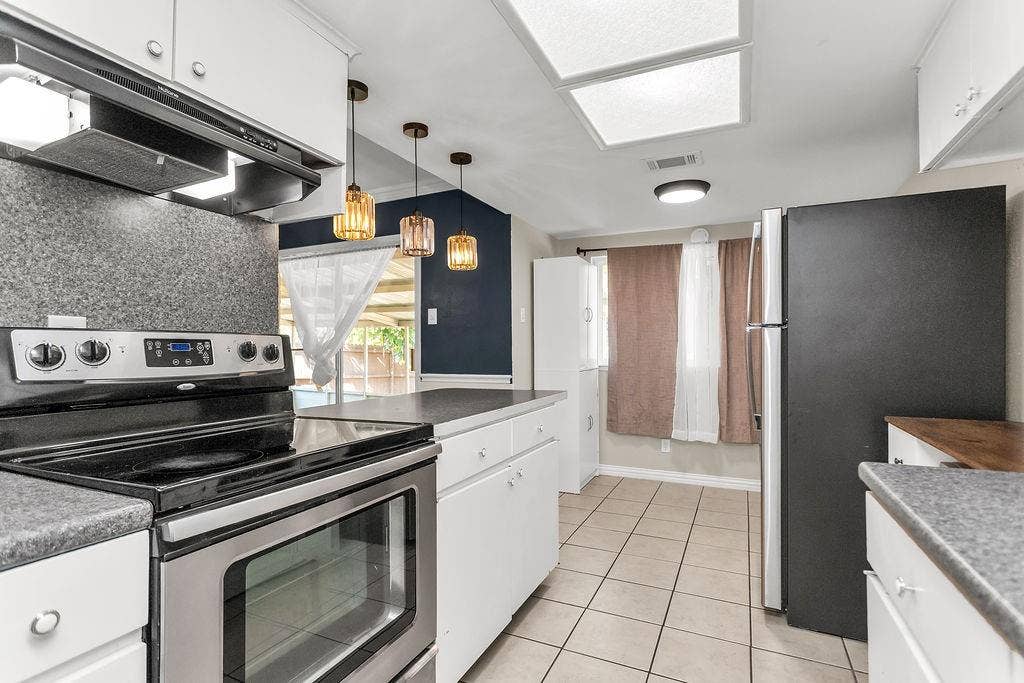 2914 Harvard Street N, Irving, TX 75062 Kitchen featuring stainless steel range, white cabinetry, dark grey countertops, and neutral tile flooring