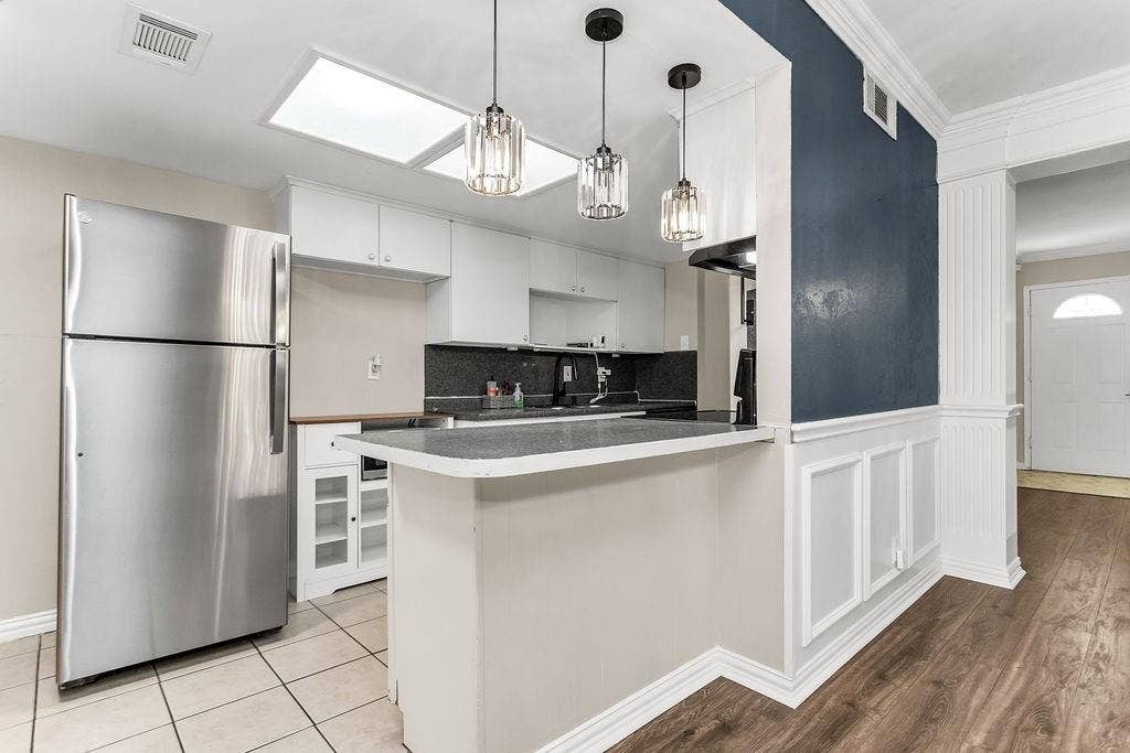 2914 Harvard Street N, Irving, TX 75062 Kitchen featuring white cabinetry, a skylight, a breakfast bar with dark countertops, and stainless steel appliances