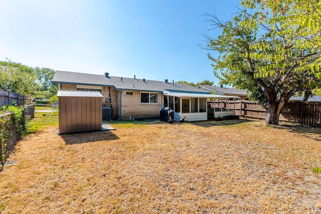 2914 Harvard Street N, Irving, TX 75062 Expansive backyard featuring a mature shade tree, privacy fencing, and a detached storage shed