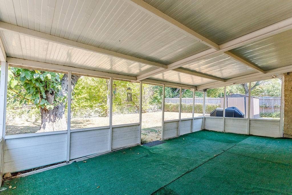 2914 Harvard Street N, Irving, TX 75062 Expansive screened-in porch with a corrugated ceiling, green outdoor carpeting, and framed panels