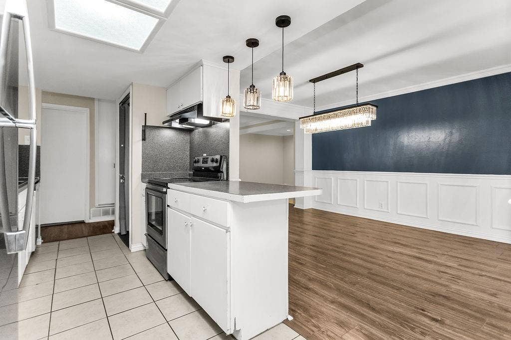 2914 Harvard Street N, Irving, TX 75062 Kitchen featuring a skylight, white cabinetry, and stainless steel refrigerator