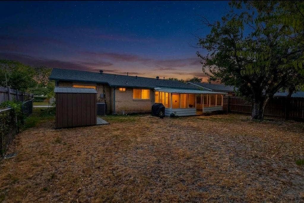 2914 Harvard Street N, Irving, TX 75062 Expansive backyard featuring a screened-in porch, mature tree, and a storage shed