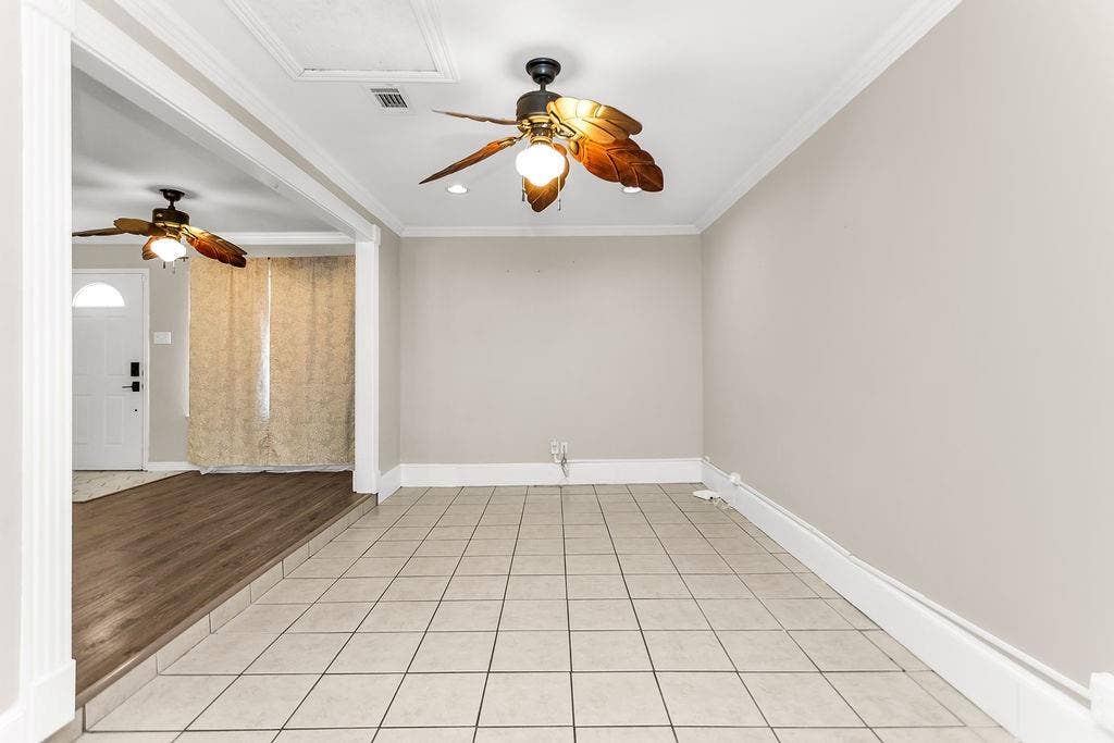 2914 Harvard Street N, Irving, TX 75062 Tiled flooring paired with wood-finish flooring, crown molding, and two ceiling fans with integrated lighting