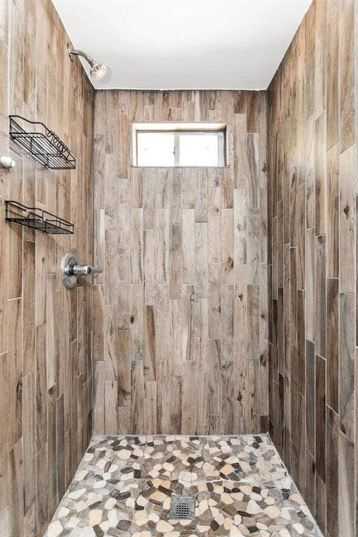 2914 Harvard Street N, Irving, TX 75062 Shower featuring wood-finish wall tile, pebble-finish flooring, and a fixed window